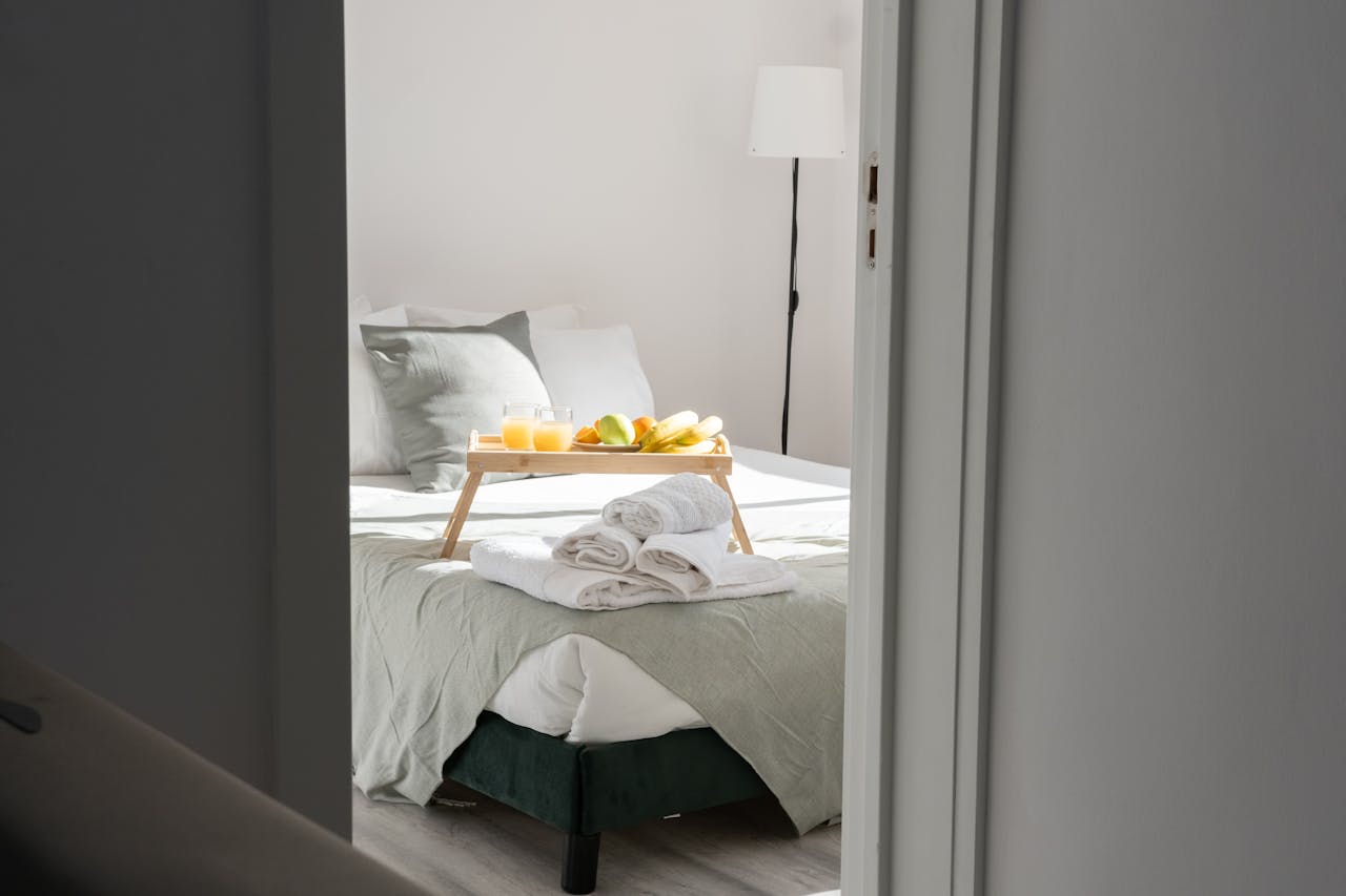 Inviting bedroom with a breakfast tray and fresh towels on the bed, perfect for a relaxing stay.
